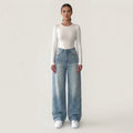 Front view of blue wide-leg jeans with dense rhinestone embellishment; white top and trainers are styling accessories
