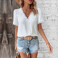 White short-sleeve top with a lace-trimmed V-neck and textured dot pattern, shown worn with denim shorts.