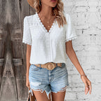 White short-sleeve top with a lace-trimmed V-neck and textured dot pattern, shown worn with denim shorts.