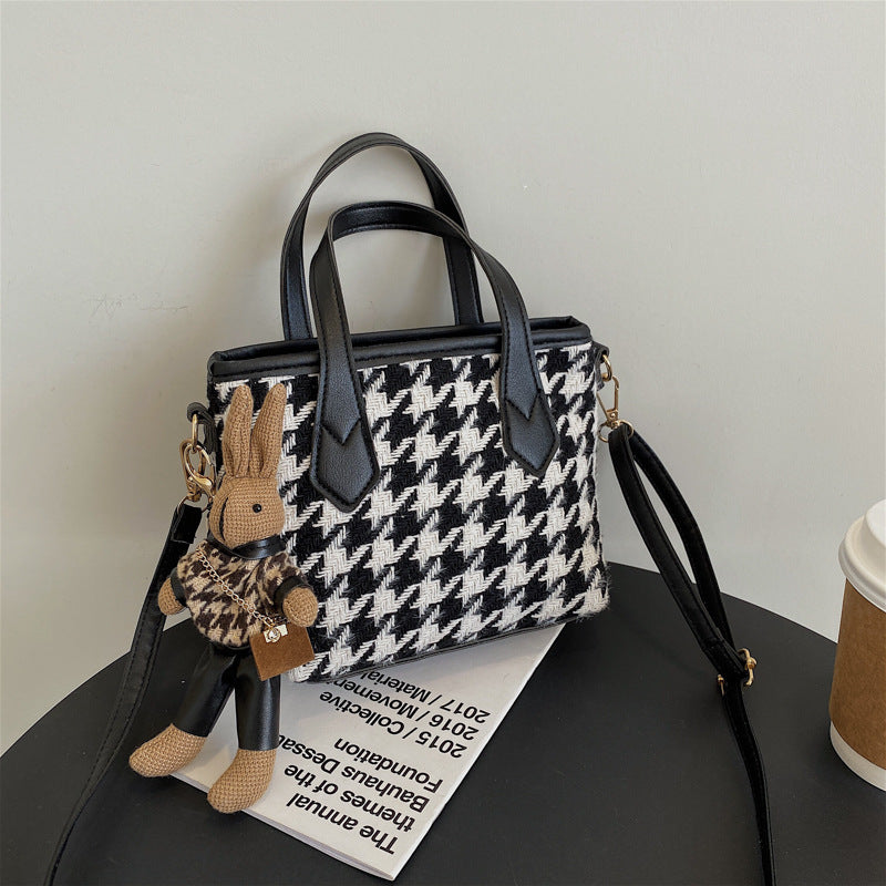 Black and cream houndstooth shoulder bag with black handles, long strap and rabbit pendant
