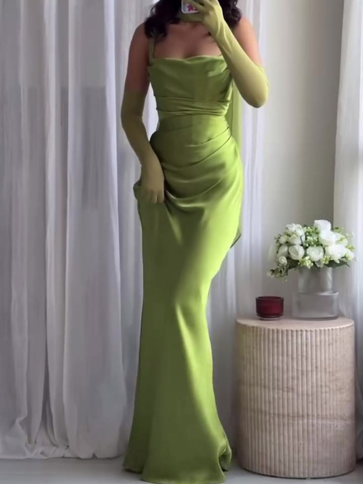Full front view of a green draped strappy maxi dress worn indoors with long glove styling