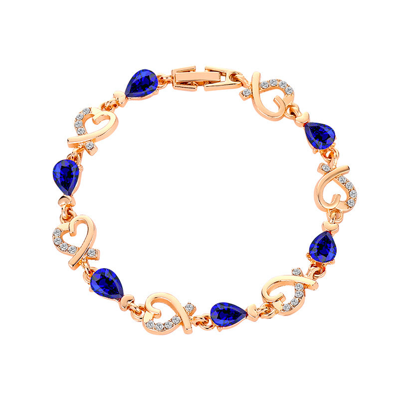 Gold-tone bracelet with blue teardrop stones, heart-shaped links and clear stone details