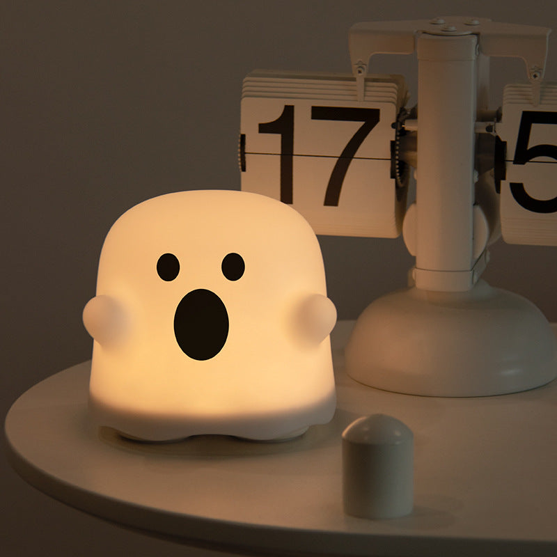Ghost-shaped decorative light with an open-mouth face, glowing on a tabletop