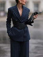 Navy pinstriped blazer shown from the front with notched lapels and a broad black waist belt.