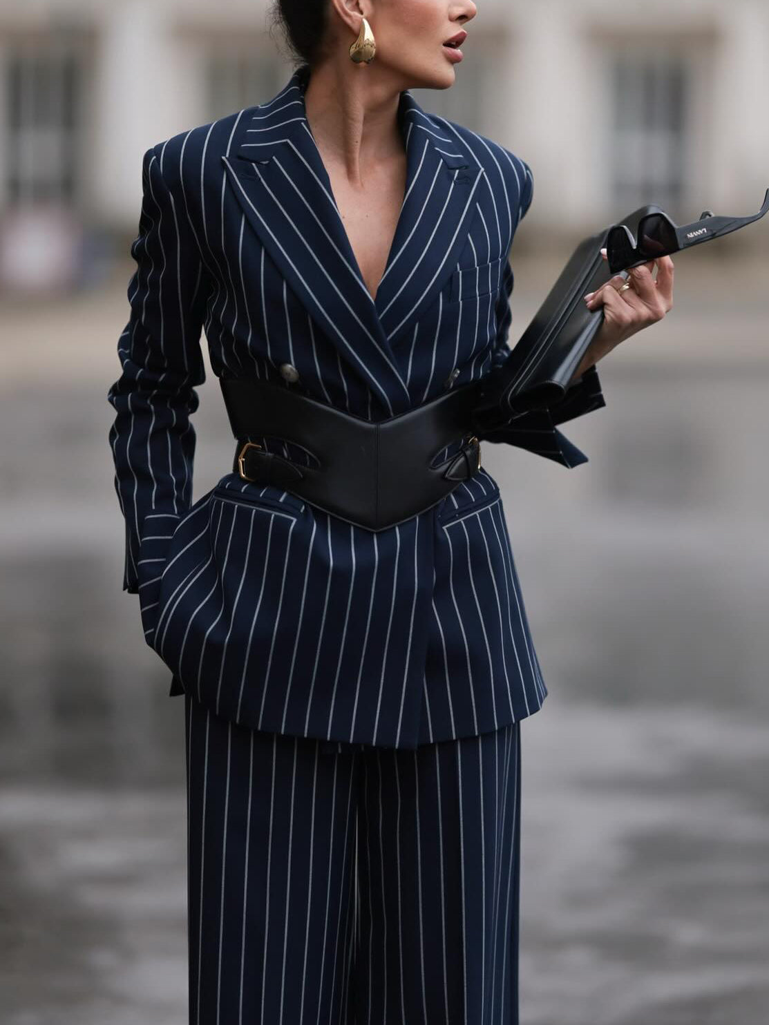 Navy pinstriped blazer shown from the front with notched lapels and a broad black waist belt.