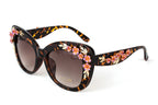 One pair of tortoiseshell cat-eye sunglasses with pink flower and gold-tone leaf embellishments on white