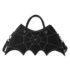 Black bat-wing-shaped crossbody bag with spider-web stitching, two handles and a shoulder strap on white.