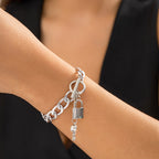 Silver-tone chain bracelet with a toggle clasp and dangling lock and key charms, shown on a wrist.