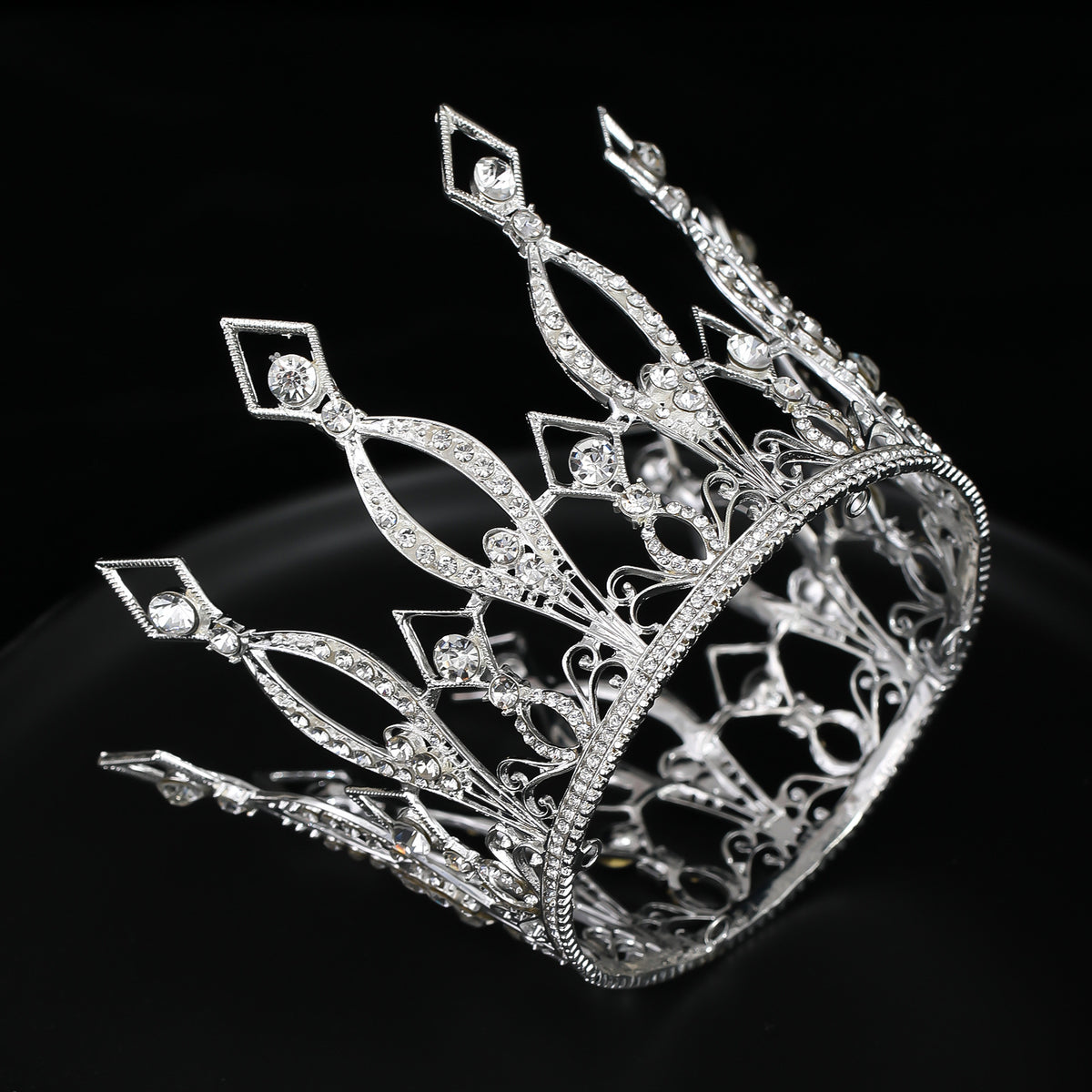 Silver-tone occasion crown with clear decorative stones, angled on a dark background.