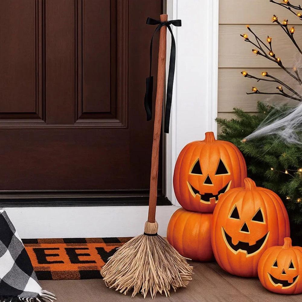 Decorative broom with a black ribbon in a Halloween doorway display.