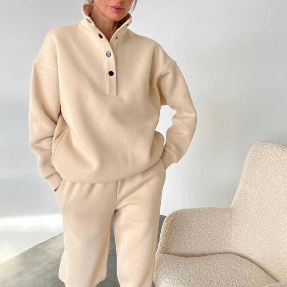 Beige button-neck pullover and matching trousers, worn indoors