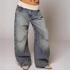 Model wearing blue wide-leg trousers with curved stitched panels and a cream contrast waistband