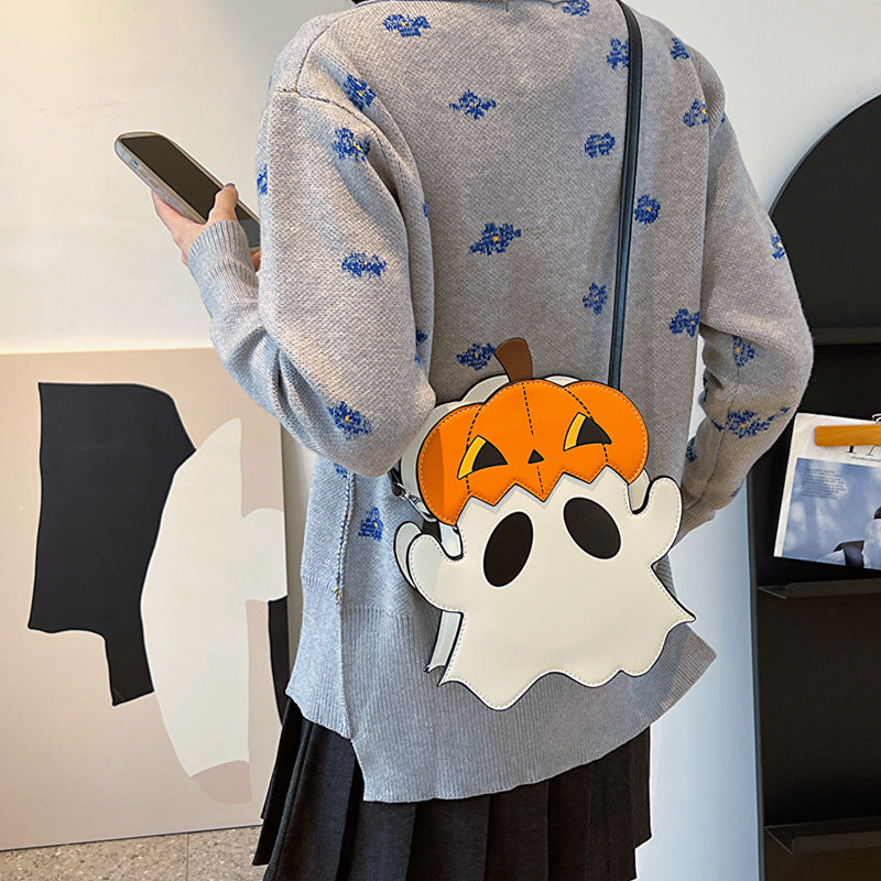 White ghost-shaped bag with an orange pumpkin hat worn at the hip over a grey cardigan.