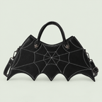 Black bat-wing crossbody bag with web stitching, two handles and strap against pale sage.