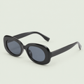 Glossy black oval sunglasses with dark lenses and wide arms against pale sage.