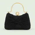 Pleated Shimmer Evening Bag in Black on a pale sage background